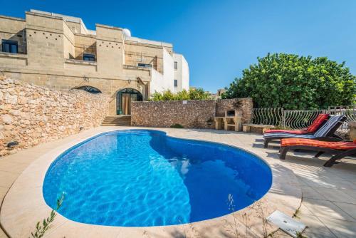 a blue swimming pool in front of a building at 3 Bedroom Holiday Home with Private Pool and Views in Nadur