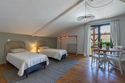 1 dormitorio con 2 camas, mesa y comedor en Les jardins de Lamourelle, en Lacquy