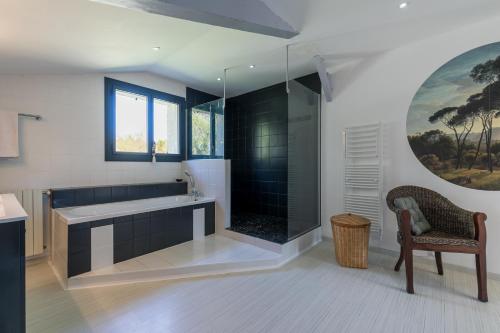 a bathroom with a tub and a glass shower at Suite familiale 2 chambres communicantes et piscine in Lacquy