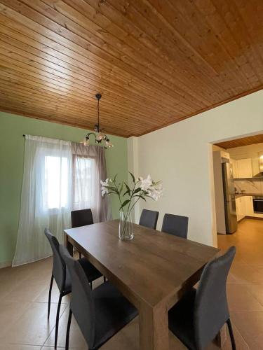 une table à manger avec des chaises et un vase de fleurs dans l'établissement Villa Olvia, à Kanallákion
