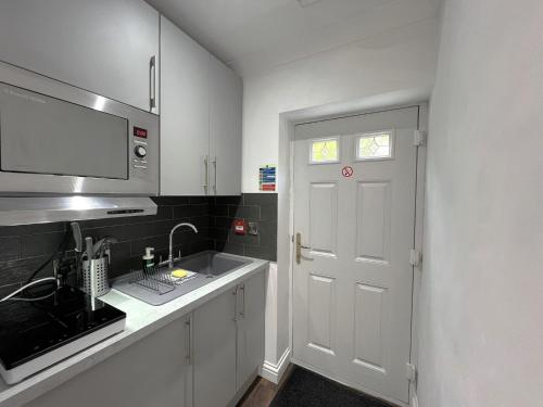 a white kitchen with a sink and a white door at Melbury Rooms & Studios in Exeter