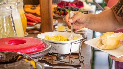 a person eating food with a spoon in a bowl of food at Pousada Das Araras in Itaúnas
