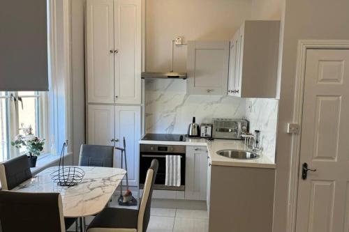 cocina con armarios blancos, mesa y fregadero en Modern 2-Bedroom Apartment-Dublin City, en Dublín