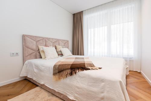 ein Schlafzimmer mit einem großen Bett und einem großen Fenster in der Unterkunft Apartamentai Monciškės "Čiki puki" in Palanga