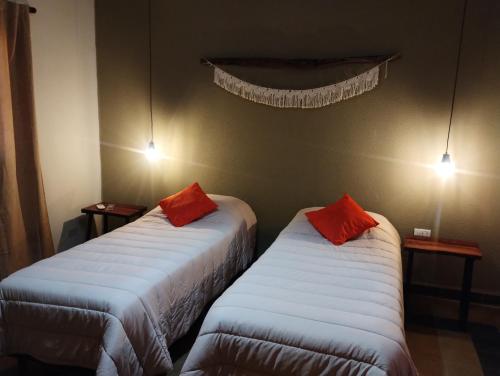 two beds in a room with red pillows on them at La Genoveva Posada entre Viñedos in Villa Unión