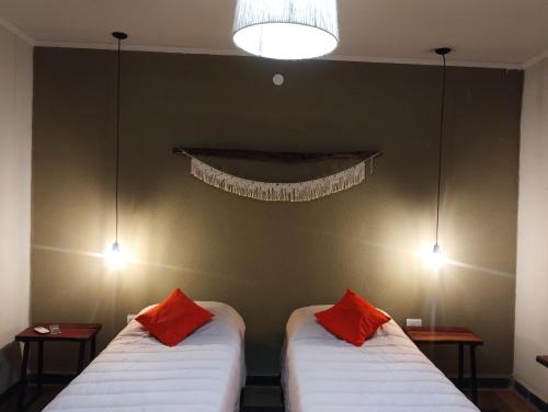 2 camas en una habitación con 2 almohadas rojas en La Genoveva Posada entre Viñedos en Villa Unión