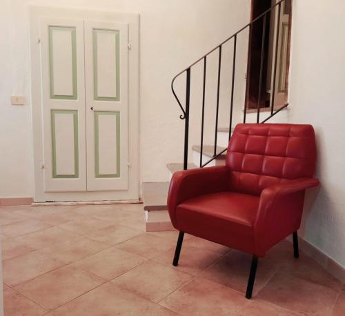 a red chair sitting in front of a door at Ninì - Casa torre nel borgo in Pontremoli