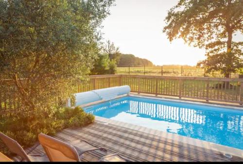 a swimming pool with a table and chairs next to a fence at Maison de campagne Piscine chauffée - 10 pers in Pontchâteau