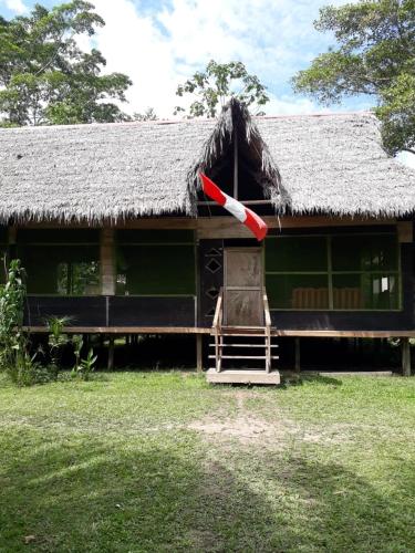 une maison avec un toit de chaume et un parapluie rouge dans l'établissement Pacaya Samiria Camping, 