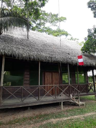 une cabane avec un toit en paille et un drapeau sur celle-ci dans l'établissement Pacaya Samiria Camping, 