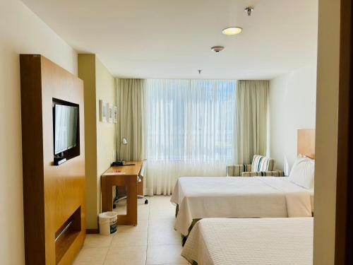 a hotel room with two beds and a television at Naoum Hotel in Brasilia