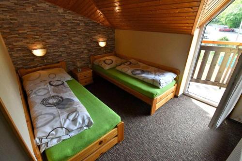 two beds in a small room with a window at Apartmánový dom PRAMEŇ in Vinné