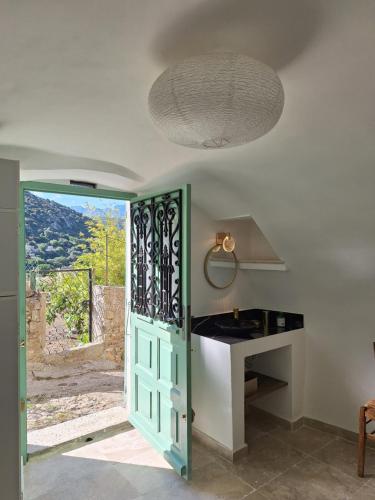 a kitchen with a green door and a table at Casa di Pilou - Maison et jardin près de la mer - Corbara in Corbara