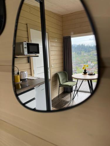 um espelho que reflecte uma cozinha e uma mesa com uma cadeira em DIDO house em Slavske