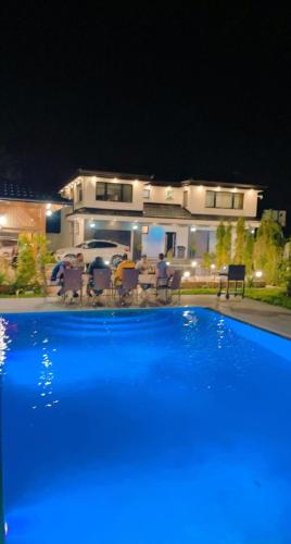 uma grande piscina azul em frente a uma casa em Villa Otes em Sarajevo