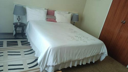 1 dormitorio con 1 cama grande con sábanas y almohadas blancas en Sharing is Caring, en Mahikeng