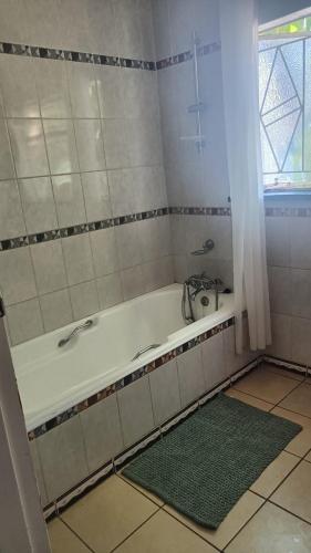 baño con bañera y alfombra verde en Sharing is Caring, en Mahikeng