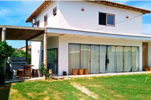 uma casa branca com grandes janelas e um quintal em Casa nova completa a poucos passos da Praia do Mutà em Porto Seguro