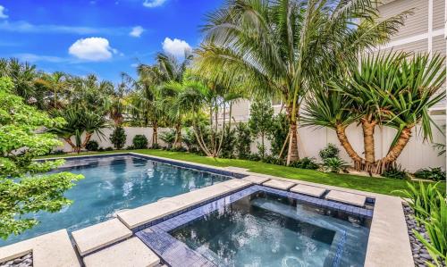 una piscina en el patio trasero de una casa con palmeras en Swanky Bubbles, 9 beds, 11 bathrooms, pet-friendly with a rooftop deck and steps away to the beach! en Holmes Beach