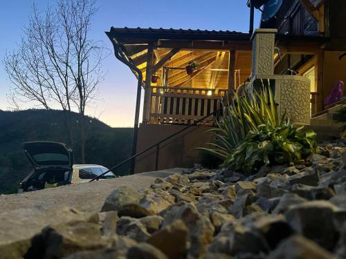 une maison avec une terrasse couverte et une cour rocheuse dans l'établissement Ljubav Stara Zaovine, à Lazići