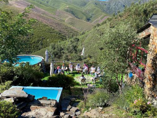 a group of people sitting in the grass near a mountain at Casa Margou in São Pedro do Sul