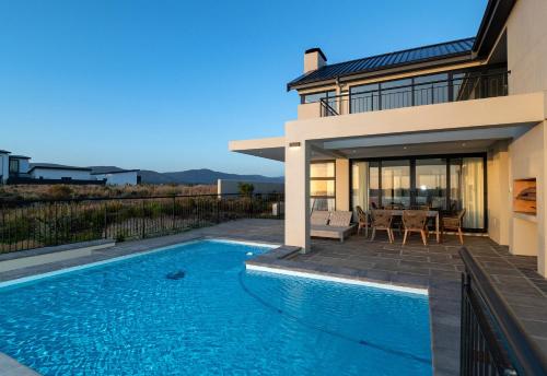 a house with a swimming pool in front of a house at Water, views, vineyards, The Zen in Hermanus
