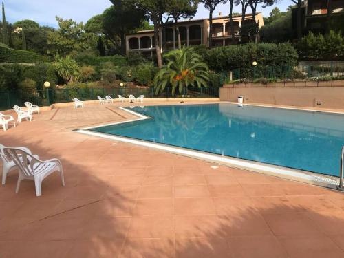 - une piscine avec des chaises blanches à côté d'un bâtiment dans l'établissement Évasion Mer & Soleil - Piscine !, à Sainte-Maxime