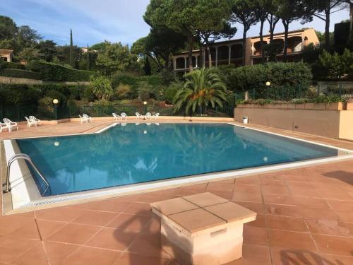 une grande piscine avec des chaises et un bâtiment dans l'établissement Évasion Mer & Soleil - Piscine !, à Sainte-Maxime