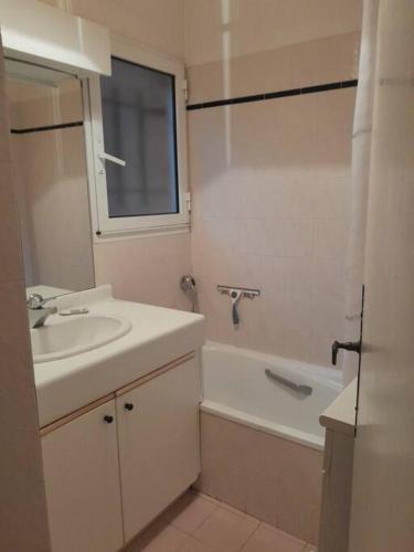 La salle de bains est pourvue d'un lavabo, d'une baignoire, d'un lavabo et d'un miroir. dans l'établissement Évasion Mer & Soleil - Piscine !, à Sainte-Maxime