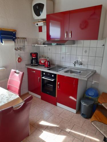 una pequeña cocina con armarios rojos y fregadero en Ferienwohnung Zawalla, en Kamminke