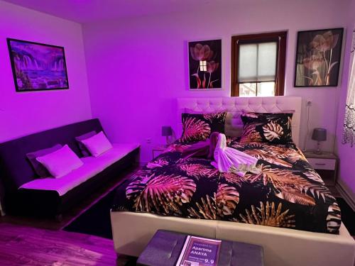 - une chambre violette avec un lit et un canapé dans l'établissement Apartma ANAYA, à Bovec