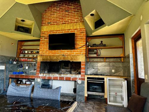 a kitchen with a brick fireplace with a tv at Vlasic Odmor - Villa Kraljica in Vlasic