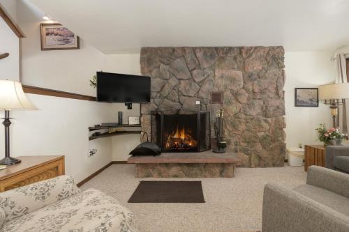 a living room with a large stone fireplace at Hideaway Village Alpine 4 in Winter Park