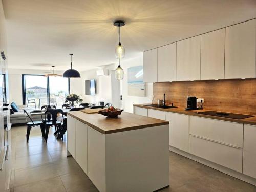 une cuisine avec des placards blancs et une salle à manger dans l'établissement Nouveau Superbe appartement - Rsd Calypso Tiuccia, à Casaglione