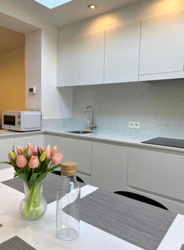 a kitchen with a table with pink flowers in a vase at Huyze Ter Vaete in Lo-Reninge