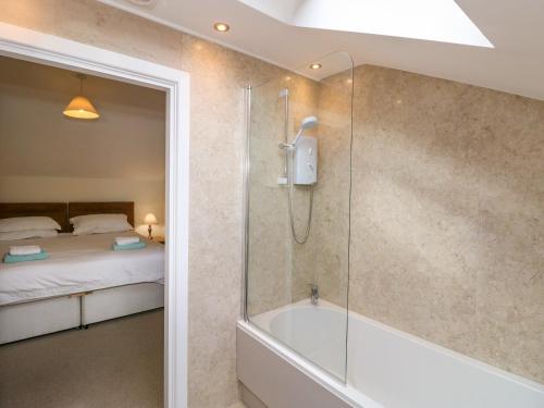 ein Badezimmer mit Dusche und Badewanne und ein Bett in der Unterkunft Rowanberry Cottage in Grasmere