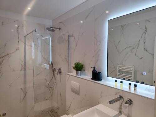 a bathroom with a shower and a sink and a mirror at Apartments Vanda in Rovinj
