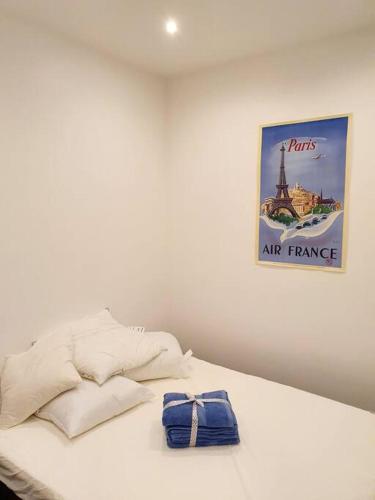 - un lit blanc avec une photo sur le mur dans l'établissement Appartement cosy & cocooning, à Asnières-sur-Seine