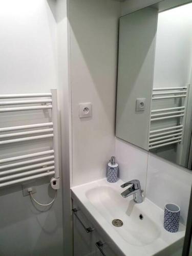 une salle de bain blanche avec un lavabo et un miroir dans l'établissement Appartement cosy & cocooning, à Asnières-sur-Seine