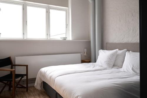 a bedroom with a bed with white sheets and two windows at South Studios by Daniel&Jacob's in Copenhagen