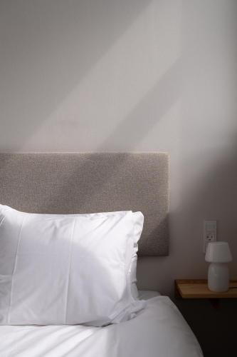 a bedroom with a white bed with a white pillow at South Studios by Daniel&Jacob's in Copenhagen