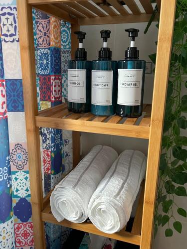 a shelf with four bottles ofodorizers and towels at Casa Morayma, Lecrin, Granada in Acequias