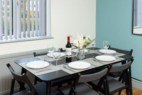 a dining room table with a bottle of wine and chairs at Leeds Beach House, Free Parkings, Sandy private backyard, 70 Inch Smart Tv, X box, Large gardens Included in Killingbeck
