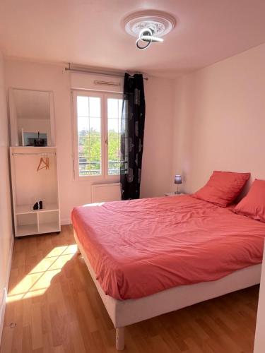 - une chambre avec un lit doté de draps rouges et une fenêtre dans l'établissement Maison de Caractère à Ballainvilliers, à Ballainvilliers