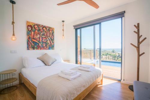 a bedroom with a bed and a large window at Caju Villas Montargil - Villa Pedra Furada in Montargil