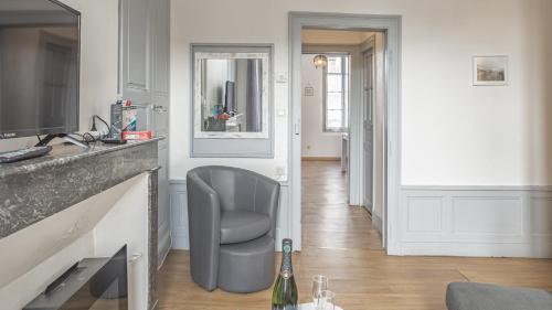 een woonkamer met een stoel en een open haard bij Preize Serenity Suite 2 - Hypercentre - 2 pers. in Troyes