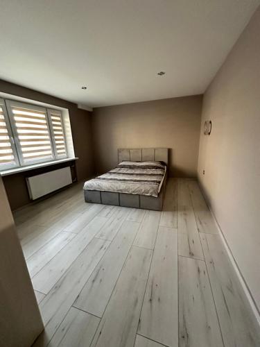 een slaapkamer met een bed en een houten vloer bij Rasa Apartment in Jelgava