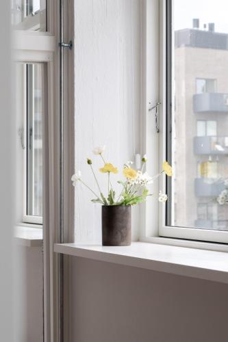 a vase with flowers sitting on a window sill at South Studios by Daniel&Jacob's in Copenhagen