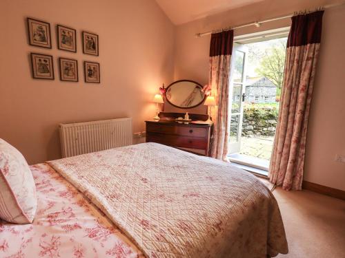 a bedroom with a bed with a dresser and a window at Beckside Studio in Patterdale