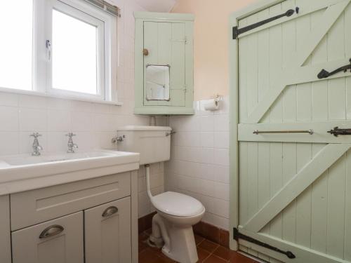a bathroom with a toilet and a sink and a window at Parc An Castle Cottage in Lizard